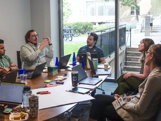 Faculty members discussing a project around a table